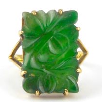 An 18ct gold ring with claw set carved floral green jade tablet, on split shoulders, size K, approx.