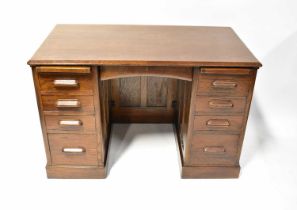 A vintage oak kneehole desk with central thin drawer flanked by two banks of four drawers, each with