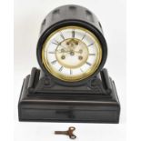 A late Victorian black slate eight day mantel clock with white enamel dial and visible escapement,