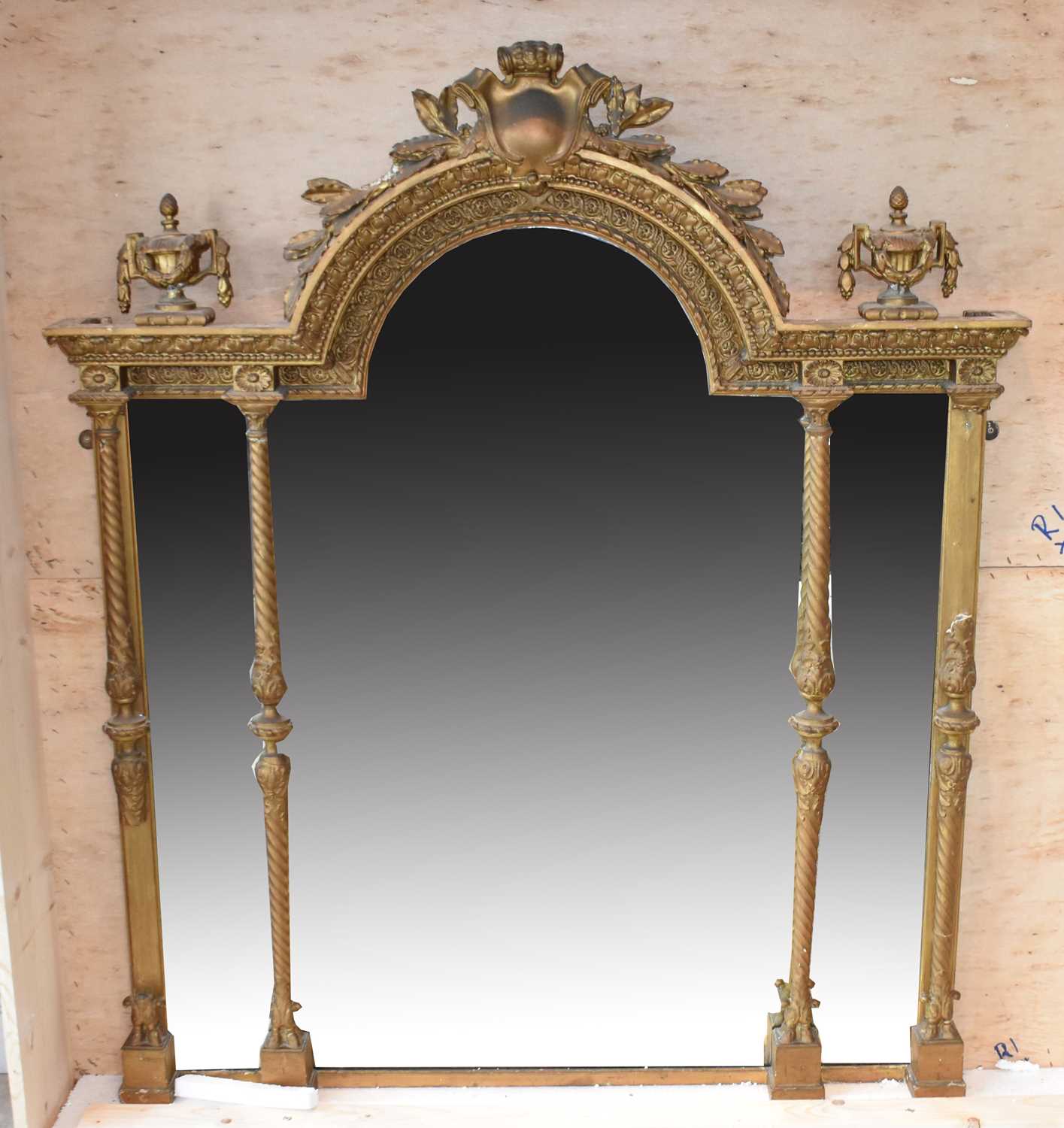 An ornate 19th century gilt wall mirror with domed crested top flanked by urns and with column
