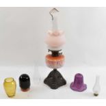 An oil lamp with pink glass reservoir and ornate metal base, height to top of chimney 66cm, with