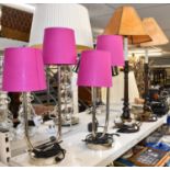 A pair of chrome two branch table lamps with lilac shades, and a pair of wooden table lamps with