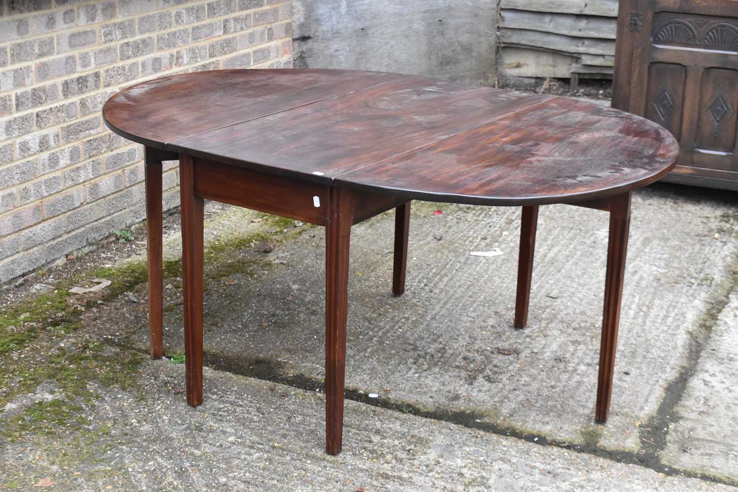 A Georgian mahogany oval drop-leaf table on square gateleg supports.