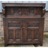 A reproduction oak court cupboard, with two pairs of carved panel doors, width 124cm.