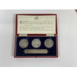 A cased set of three commemorative coins, plus stamped silver plaque 'The Three British Kings of