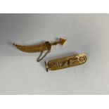 Two yellow metal brooches, one decorated with hieroglyphs and one modelled as a dagger, approx 9.