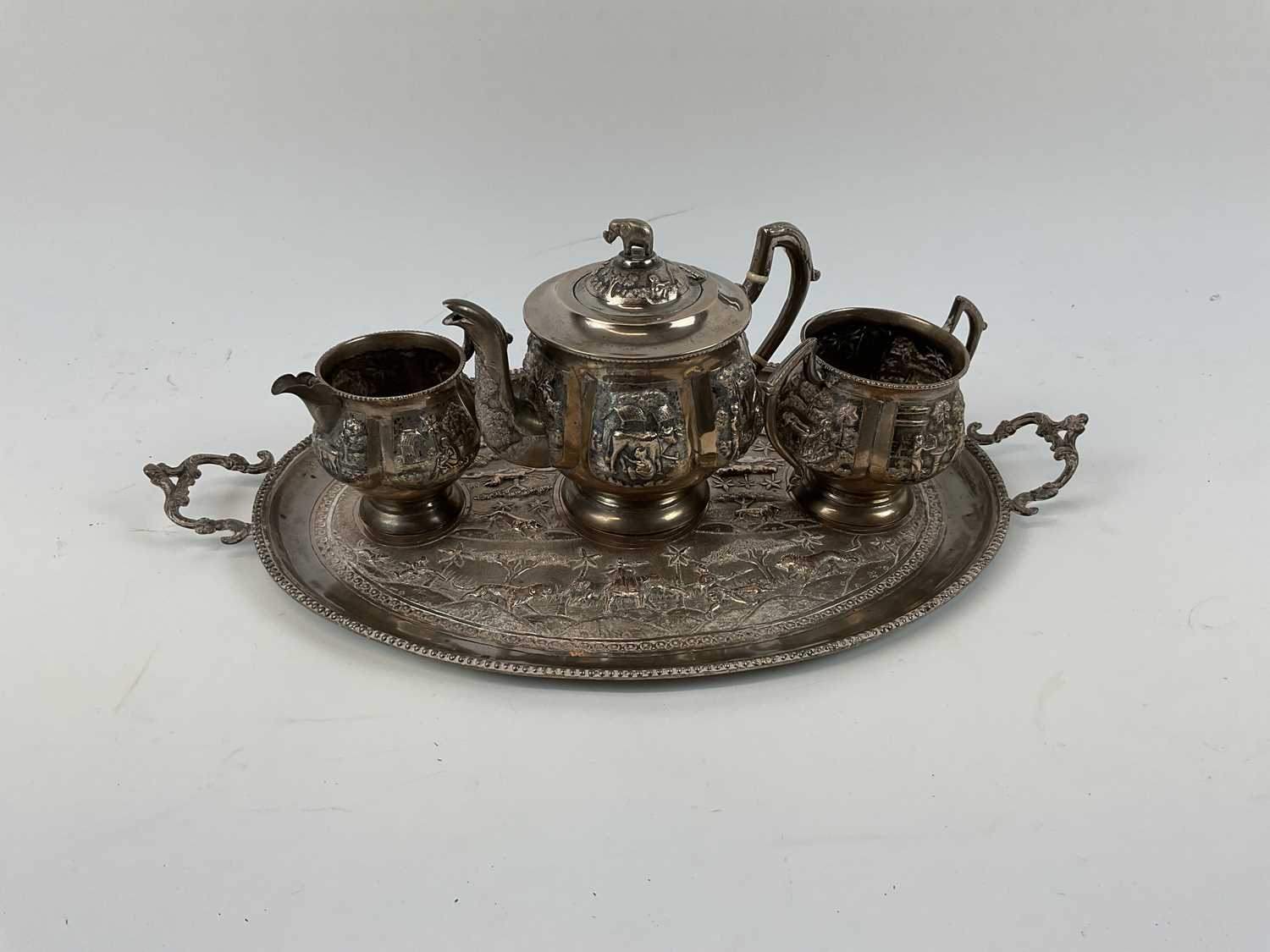 X An Indian silver four piece tea service, decorated with typical scenes of animals and village