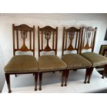 A set of four carved oak upholstered dining chairs with central urn decoration on pad feet.