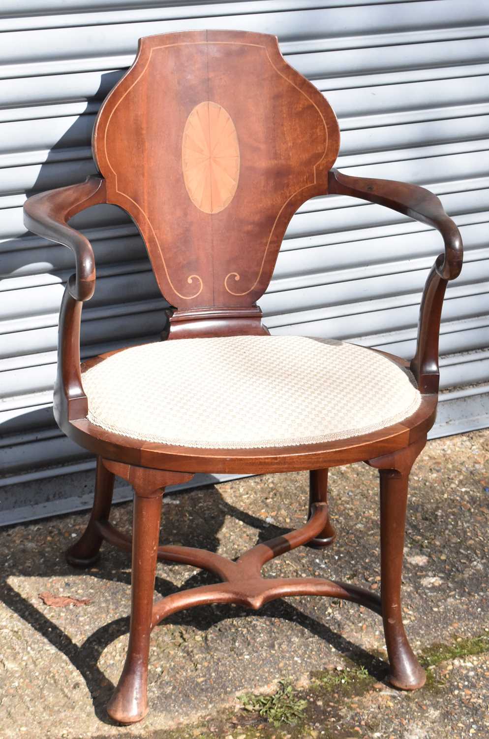 An Edwardian inlaid mahogany open arm elbow chair on cabriole supports united by a stretcher.