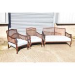 An early 20th century mahogany bergère suite comprising sofa and two armchairs (3).