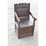 An 18th/19th century oak wainscot type chair with panel back, open arms and hinged seat.Condition