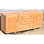 ERCOL; a mid century light oak sideboard with three central drawers flanked by cupboard doors,