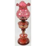 A Victorian ruby glass oil lamp with painted decoration, height 54cm.