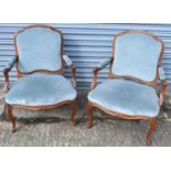 A pair of French carved walnut framed open arm elbow chairs on cabriole supports.