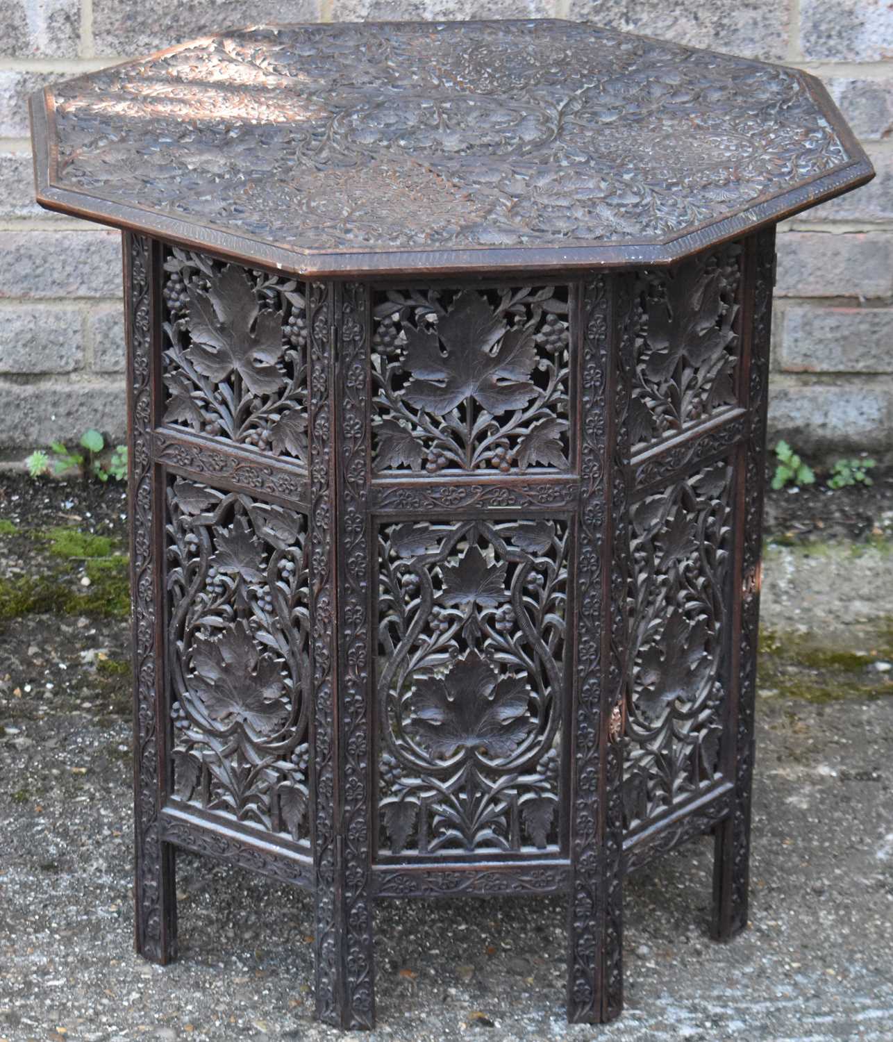 A Moorish carved hardwood octagonal table on folding base, 63cms high and 60cms diameter
