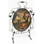 An Art Nouveau wrought iron framed firescreen inset with central oval painted bevelled mirror,