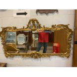 A decorative gilt framed wall mirror with foliate scroll pierced border and three sectioned plate,