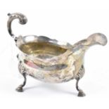 A Victorian hallmarked silver sauce boat with engraved crest and flying scroll handle, London