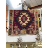 A hand woven kilim hanging/carpet decorated with geometric designs.