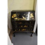 A 1920s black lacquer and gilt chinoiserie decorated bureau with fall front above three long drawers