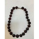 A vintage hand tied dark cherry amber bead necklace, length 38cm, each bead approx 15 x 13mm, approx