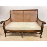 An early 20th century single caned Bergère two seater settee, raised on scrolling cabriole front