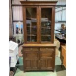 An Edwardian oak bookcase on cupboard, the upper section with twin glazed doors above a base of