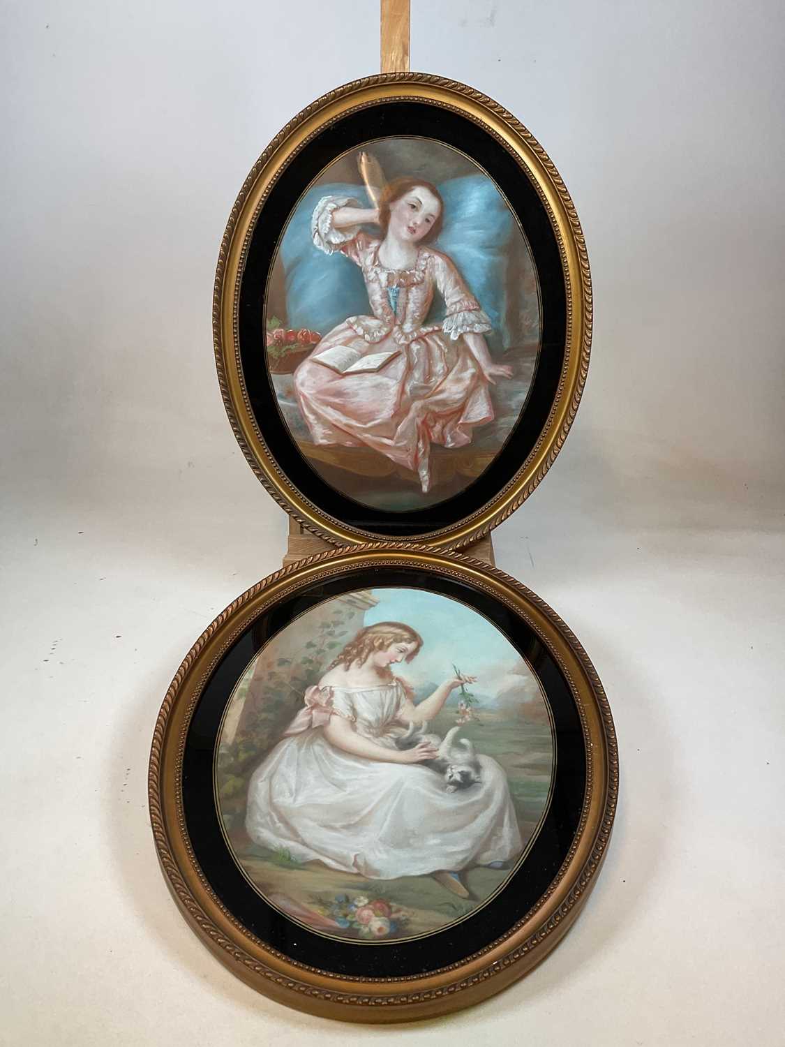 UNATTRIBUTED; a pair of oval pastels, one depicting a young lady playing with her cat, the other