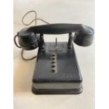A vintage black bodied wall mounted telephone with five buttons and no dial.