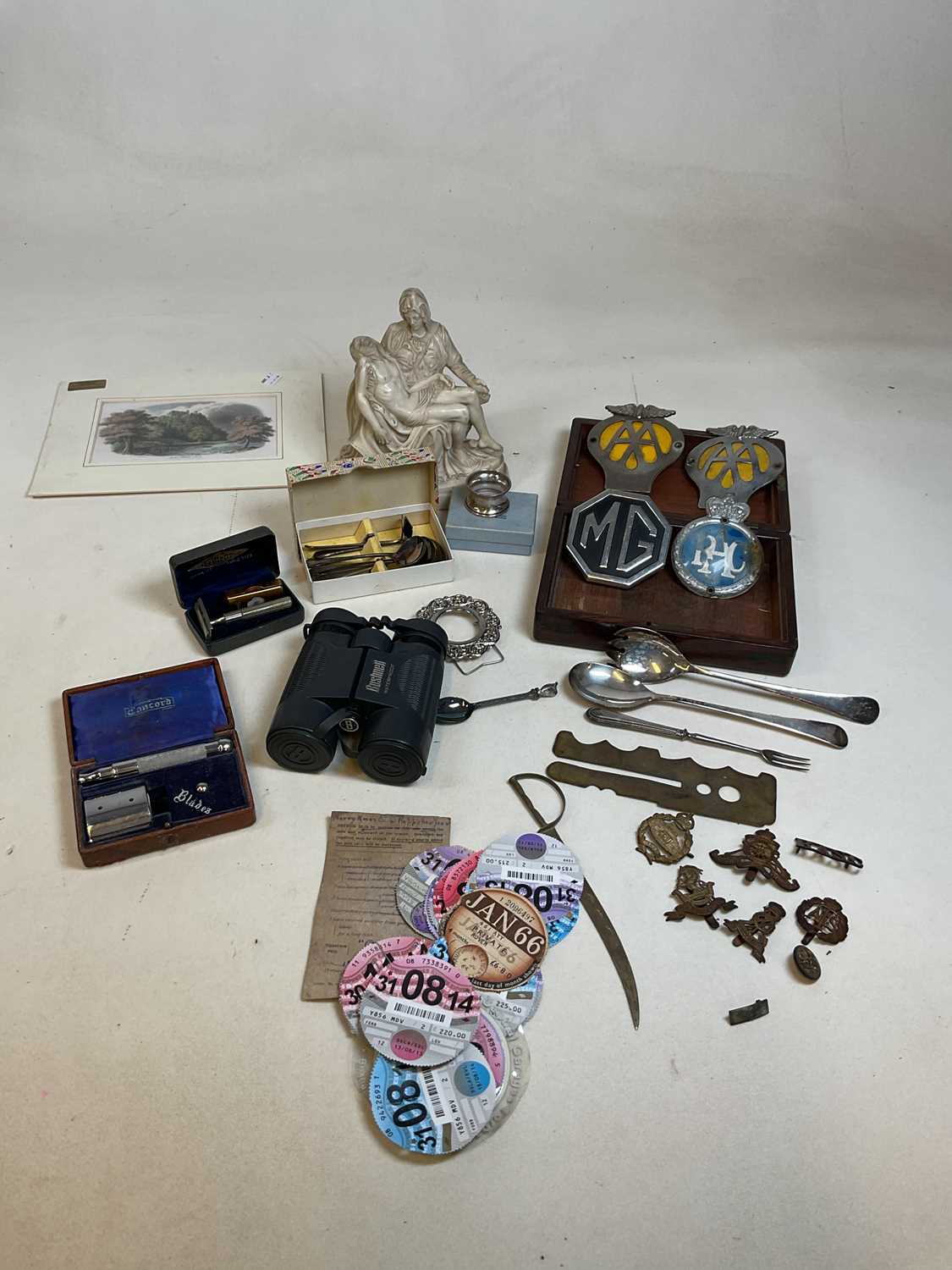 A group of collectors' items including car badges, rosewood box, military cap badges, tax disc,