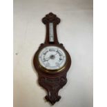 An Edwardian carved oak and aneroid wheel barometer.