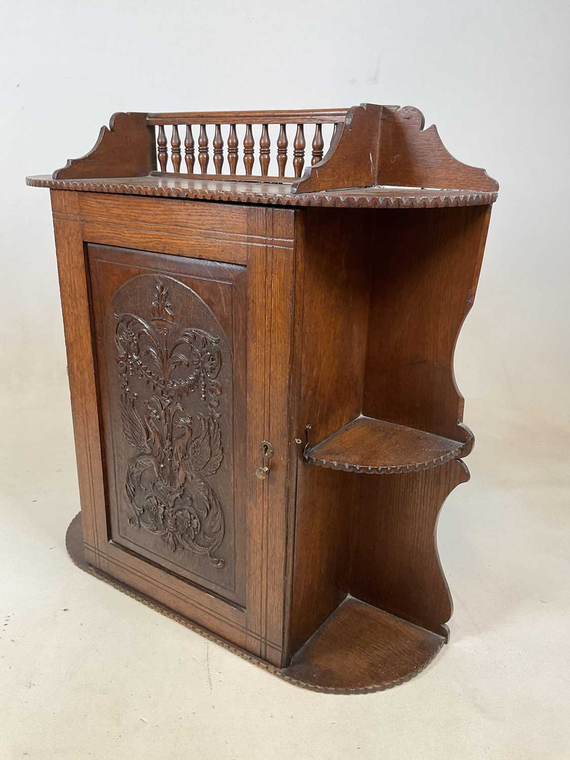 A circa 1900 oak hanging cabinet with spindle gallery above intricately carved hinged door enclosing - Image 3 of 8
