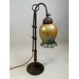 An Art Nouveau brass mounted adjustable table lamp with iridescent tinted glass shade.