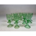 A set of ten early 20th century iridium tinted green glasses and a similar set of six, heights