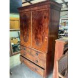 A George IV mahogany linen press with twin oval panel doors above two short and two long drawers (