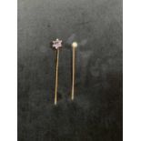 Two 9ct gold stick pins, one set with a cultured pearl, the other set with central pale purple stone
