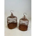 An unusual Chinese carved sandalwood birdcage set with two small porcelain water feeders to the