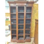 A breakfront open bookcase of narrow proportions made from antique mahogany set with adjustable