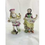 A pair of 19th century porcelain figural salts, each holding a basket with recess, presumably for