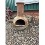 A terracotta chiminea on stand.