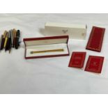 A group of pens, including Must de Cartier, a boxed ballpoint pen with booklet, a Parker pen with