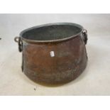A beaten copper tapering circular vessel with twin iron handles, width approx. 45cm.