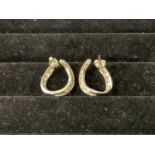 A pair of white metal and diamond set hoop twist earrings, each set with thirteen round brilliant