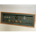 A framed and glazed display of cap badges and helmet plates relating to the Royal Marines, including