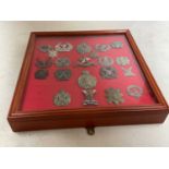 A framed and glazed display of Scottish regiment cap badges, including Highland Regiment, The