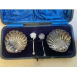 A cased pair of late Victorian hallmarked silver shell moulded salts with matching spoons, Chester