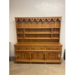 A contemporary blonde oak dresser, the boarded plate rack above three frieze drawers and a pot board