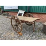 A French costamonger's cart with iron trimmed wooden spoked wheels and flat bed platform, traces