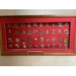 A framed and glazed display of various cap badges, including Artillery and the Hussars.