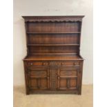 A reproduction oak dresser with boarded plate rack and carved detail, width 137cm.